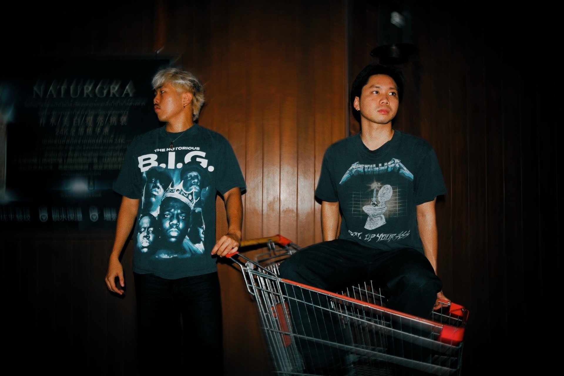 Two friends in vintage band tees with a shopping trolley