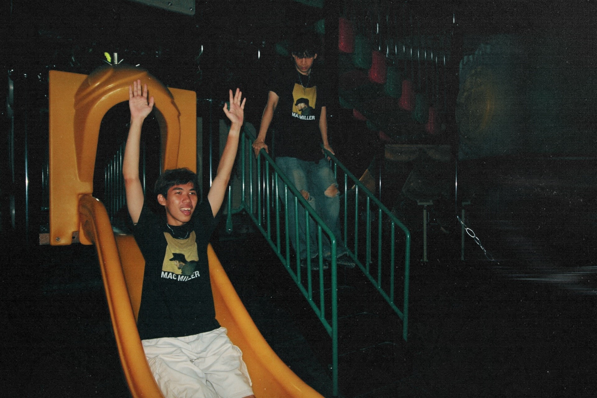 A Mac Miller tee on a playground slide at night